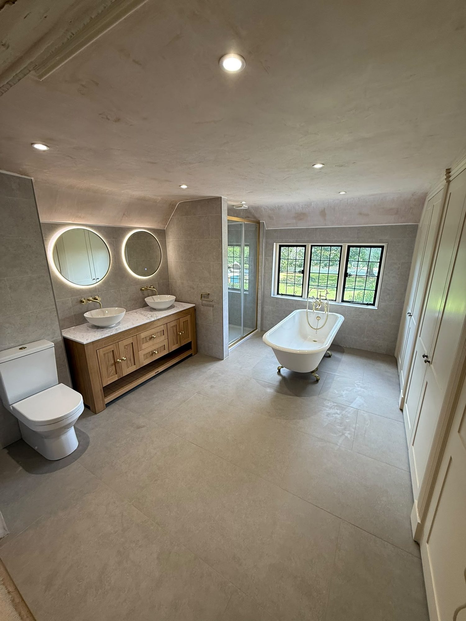 Finished bathroom with tiled walls and floor, freestanding bath, twin countertop basins and shower enclosure