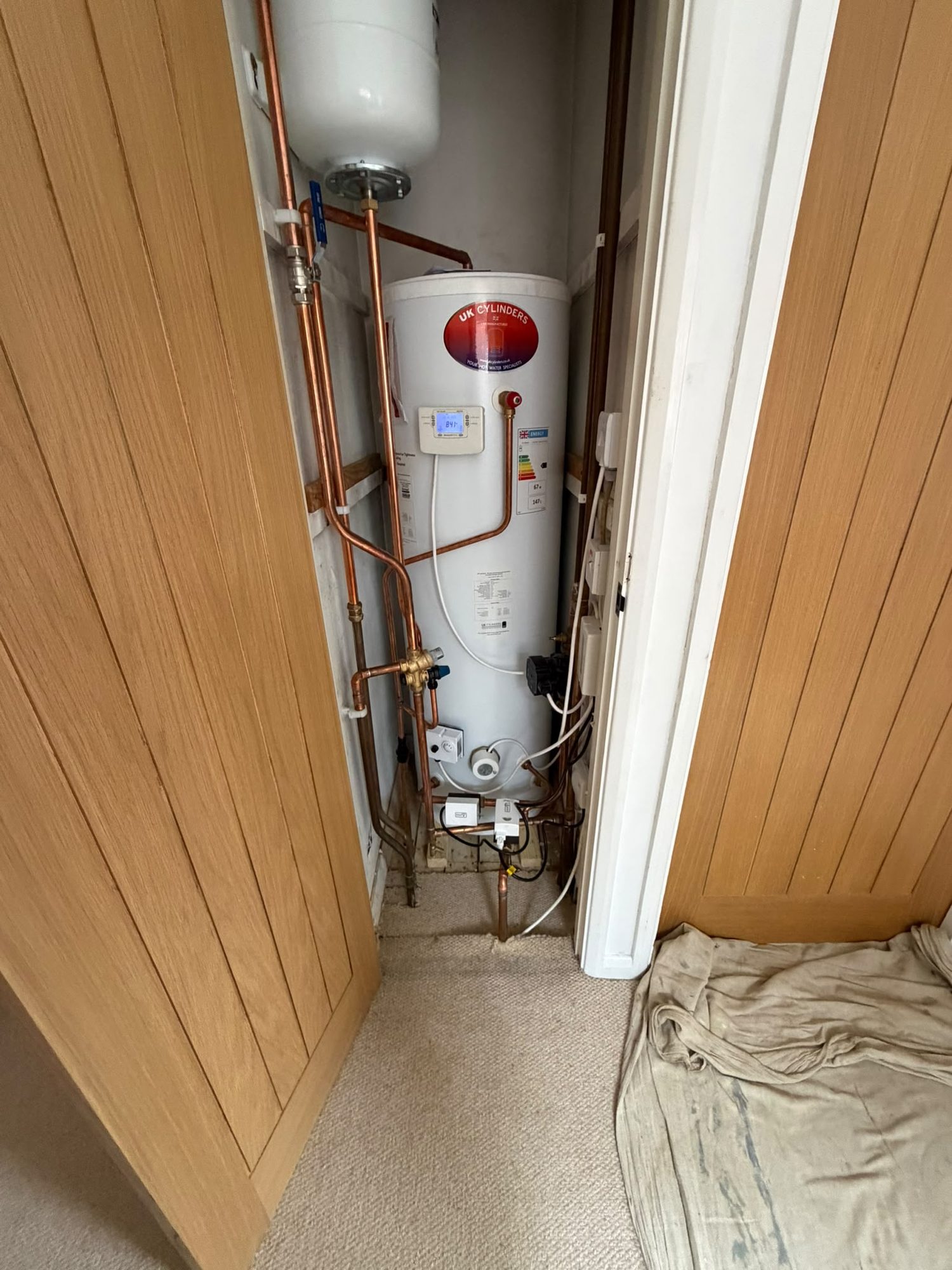 Unvented hot water cylinder fitted into an airing cupboard with digital controls